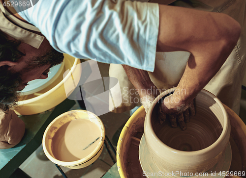 Image of Creating a jar or vase of white clay close-up. Master crock.