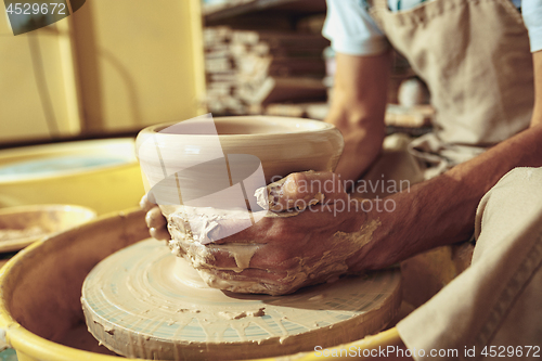 Image of Creating a jar or vase of white clay close-up. Master crock. Man hands making clay jug macro.