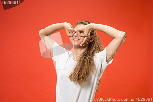 Image of The happy woman standing and smiling against red background.