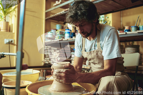 Image of Creating a jar or vase of white clay close-up. Master crock.