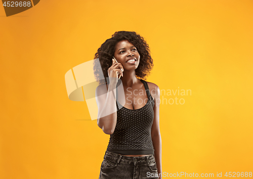 Image of The happy business woman standing and smiling against gold background.