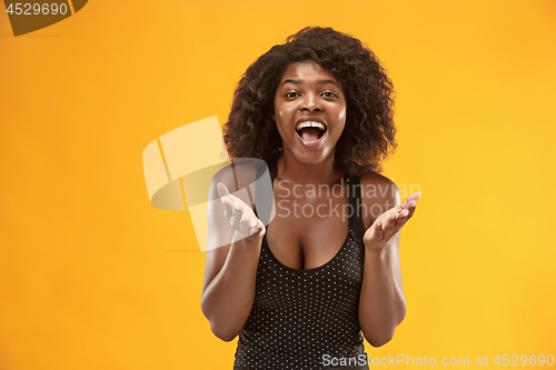 Image of The happy business woman standing and smiling against gold background.