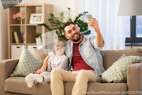 Image of father and daughter taking selfie at home