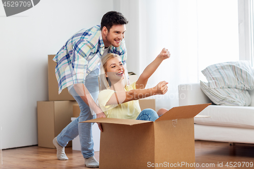 Image of happy couple having fun with box at new home