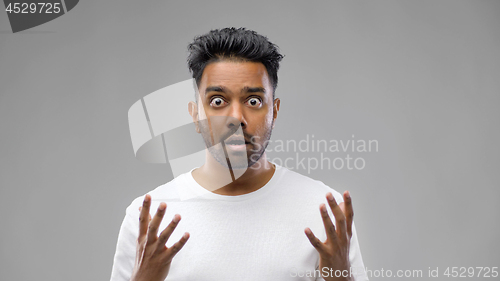 Image of shocked indian man over grey background