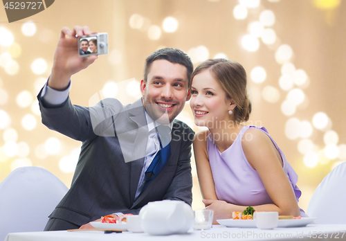 Image of happy couple taking selfie at sushi restaurant