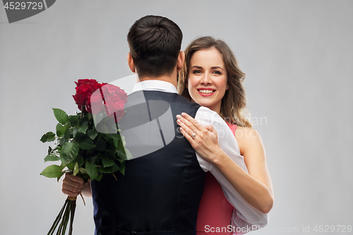 Image of woman with engagement ring and roses hugging man