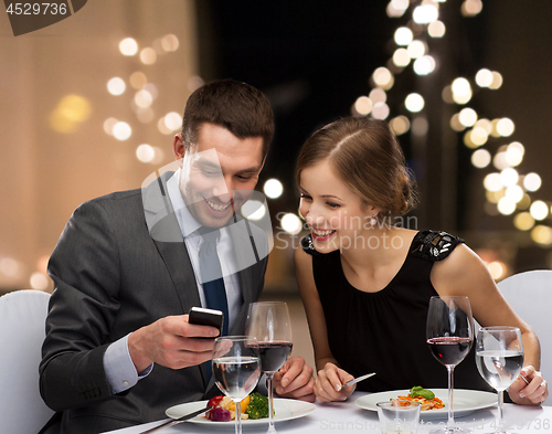 Image of couple with smartphone eating at restaurant