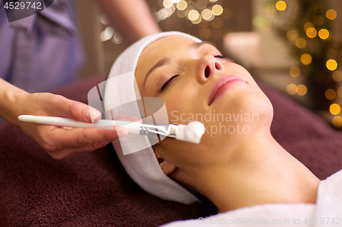 Image of beautician applying facial mask to woman at spa