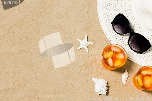 Image of cocktails, sun hat and sunglasses on beach sand