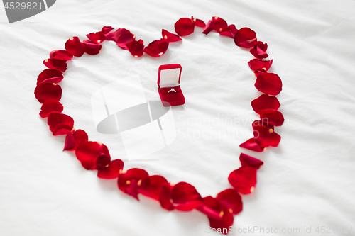 Image of heart made of petals and diamond ring in gift box