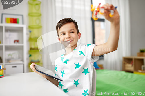 Image of boy with tablet computer and toy airplane at home