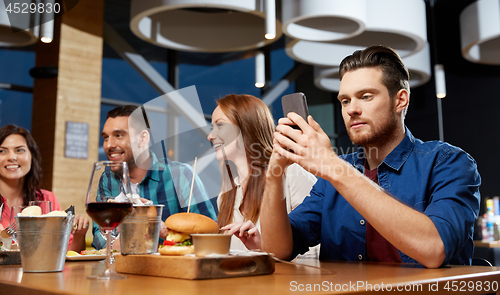 Image of man messaging on smartphone at restaurant