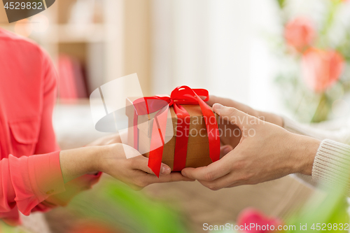 Image of close up of male and female hands with gift box