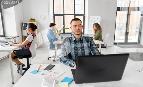 Image of creative man with laptop working at office