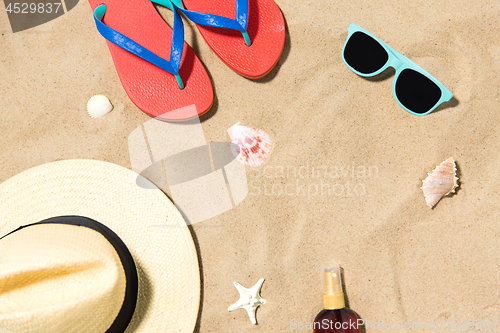 Image of straw hat, flip flops and sunglasses on beach sand