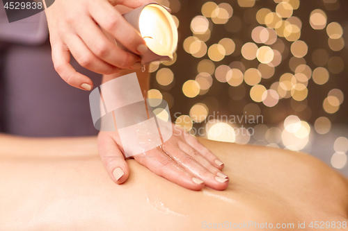 Image of woman doing back massage with hot oil at spa