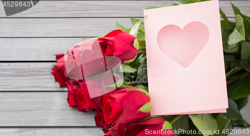 Image of close up of red roses and greeting card with heart