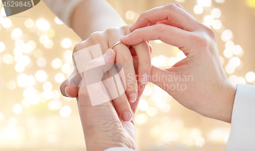 Image of close up of lesbian couple hands with wedding ring