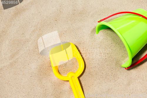 Image of close up of toy bucket and shovel on beach sand