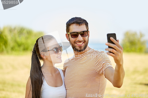 Image of happy couple taking selfie by smartphone in summer