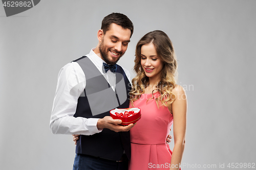 Image of happy couple with chocolate box in shape of heart