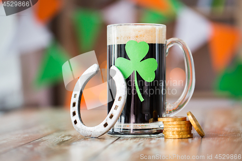 Image of shamrock on glass of beer, horseshoe and coins