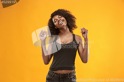 Image of The happy business woman standing and smiling against gold background.