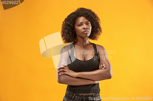 Image of The serious business woman standing and looking at camera against gold background.