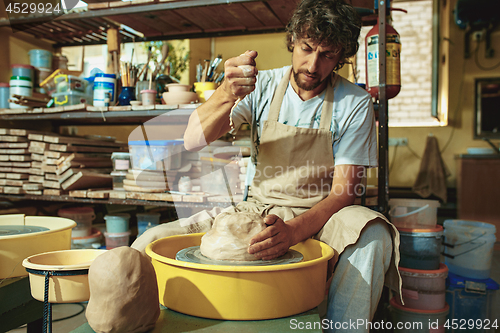 Image of Creating a jar or vase of white clay close-up. Master crock.