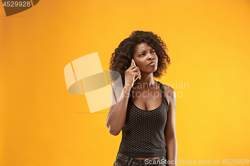Image of The happy business woman standing and smiling against gold background.