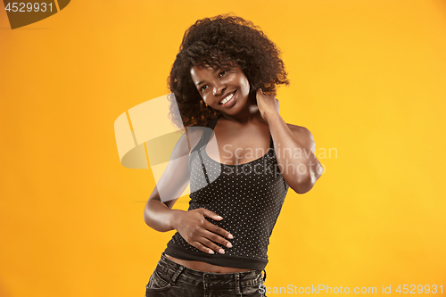 Image of The happy business woman standing and smiling against gold background.