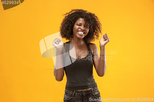 Image of The happy business woman standing and smiling against gold background.