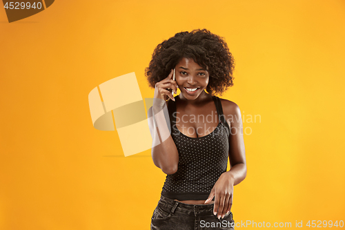 Image of The happy business woman standing and smiling against gold background.
