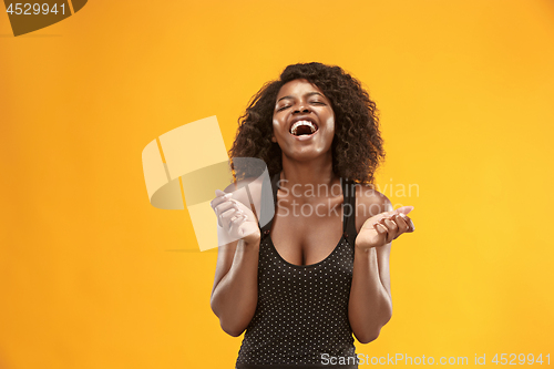 Image of The happy business woman standing and smiling against gold background.