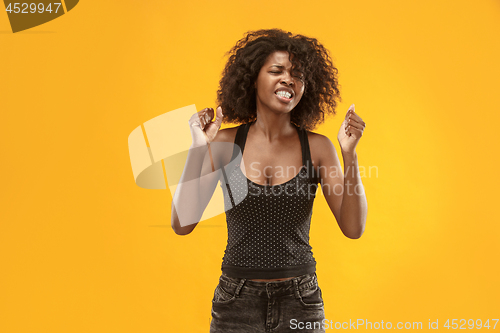 Image of Portrait of an angry woman looking at camera isolated on a gold background