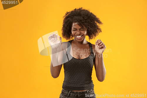 Image of Portrait of an angry woman looking at camera isolated on a gold background