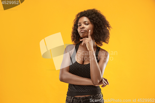 Image of The serious business woman standing and looking at camera against gold background.