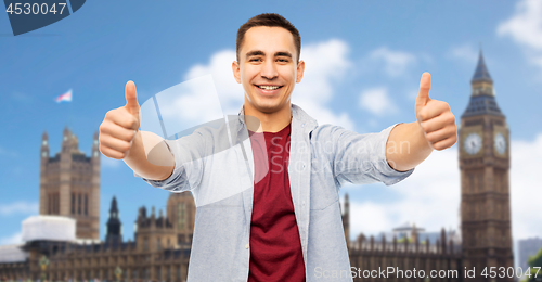 Image of happy young man showing thumbs up over london