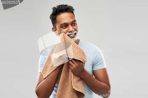 Image of man removing shaving foam from face by towel