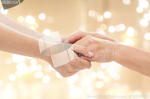 Image of close up of senior and young man holding hands