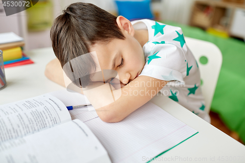 Image of tired student boy sleeping on table at home