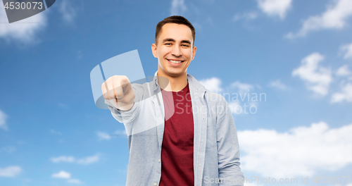 Image of man pointing finger to you over blue sky