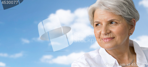 Image of portrait of smiling senior woman over blue sky