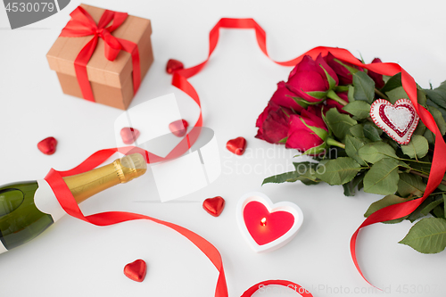 Image of close up of champagne, gift, candies and red roses