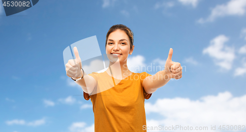 Image of teenage girl in t-shirt showing thumbs up over sky