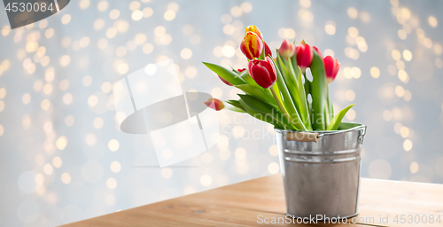 Image of red tulip flowers in bucket on table over lights