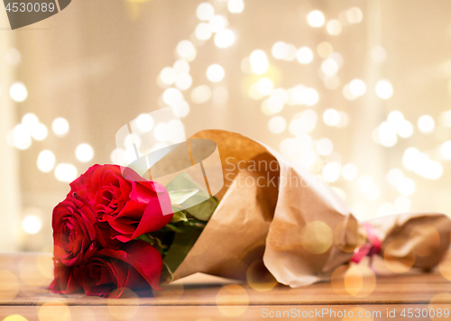 Image of close up of red roses bunch wrapped into paper