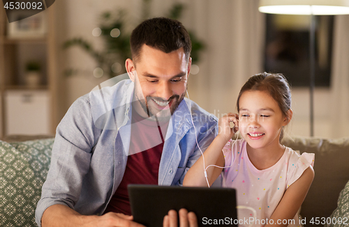 Image of father and daughter listening to music on tablet