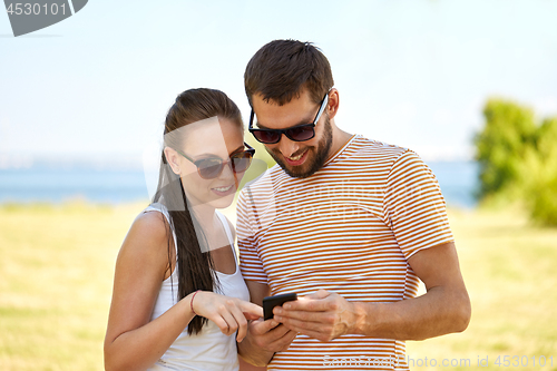 Image of happy couple with smartphone in summer